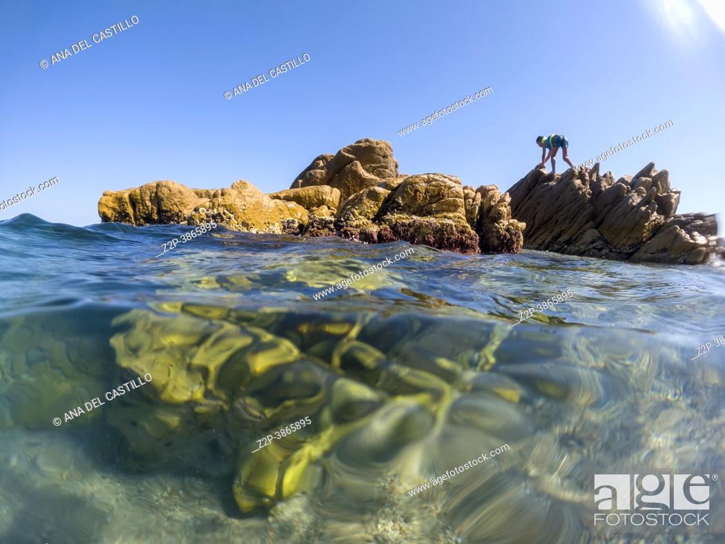Stock Photo: Platja d Aro beach underwater Costa Brava Girona Catalonia Spain. Boy on rocks.