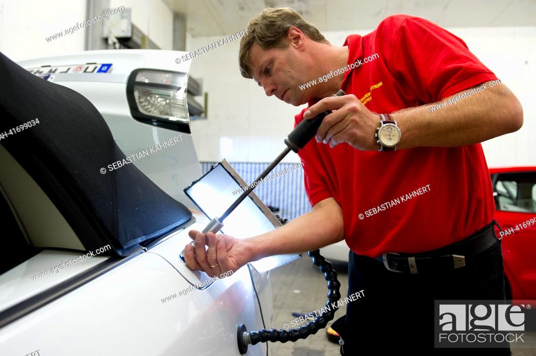 Stock Photo: Car engineer Gvido Stalidzans removes a dent in a car that was caused by a hailstorm in Peine, Germany, 13 August 2013. Dent doctors go wherever storms have.