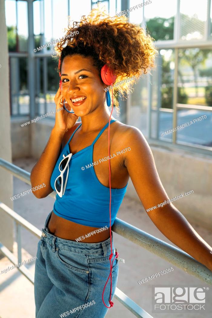Photo de stock: Portrait of smiling young woman listening music with headphones.