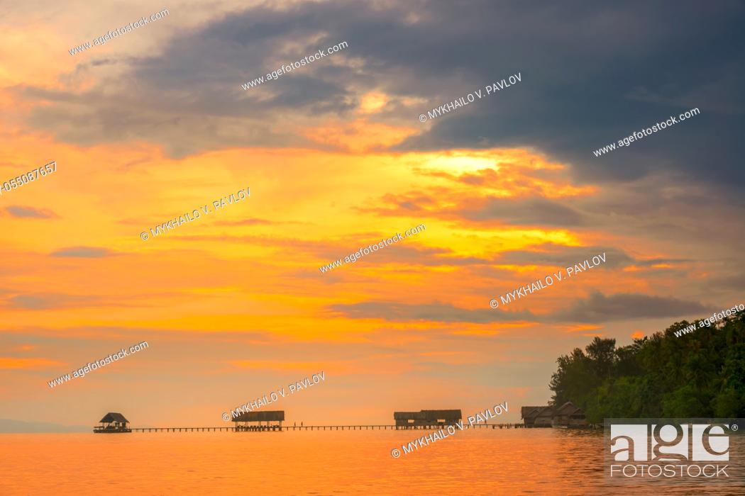 Stock Photo: Indonesia. Raja Ampat archipelago. Long bridges, a pier and several huts. Colorful sunset sky.