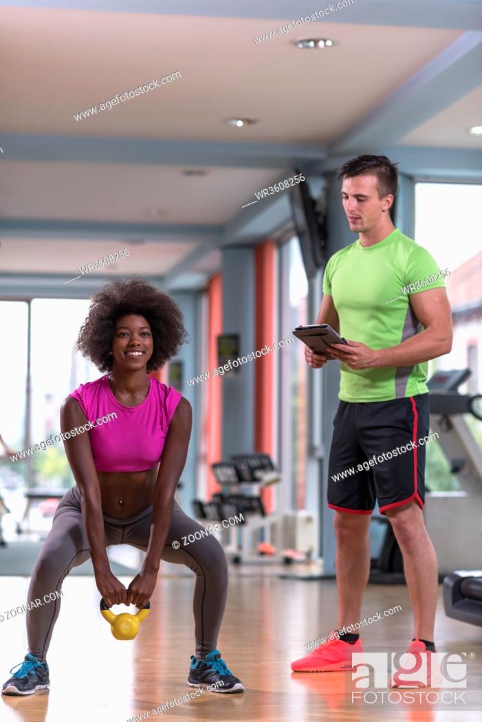Stock Photo: healthy young couple in crossfit gym weights workout with personal trainer.