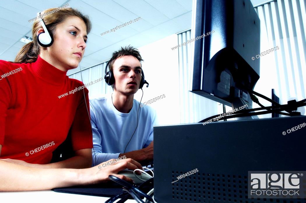 Imagen: Teenage girl wearing headphones using a computer with a teenage boy sitting beside her.