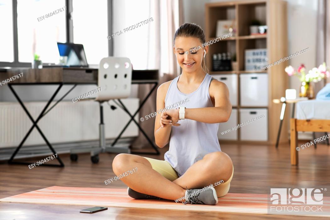 Stock Photo: teenage girl with gadgets exercising at home.