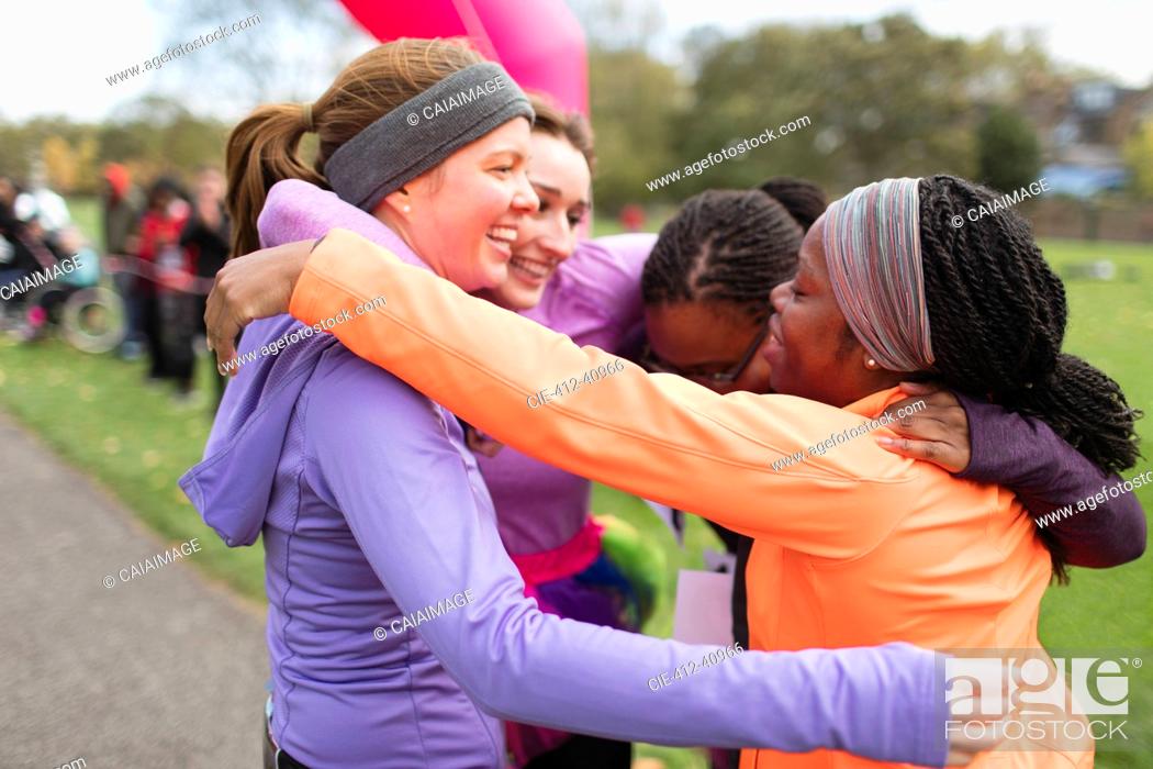 Stock Photo: Happy female runners hugging at charity run finish line, celebrating.