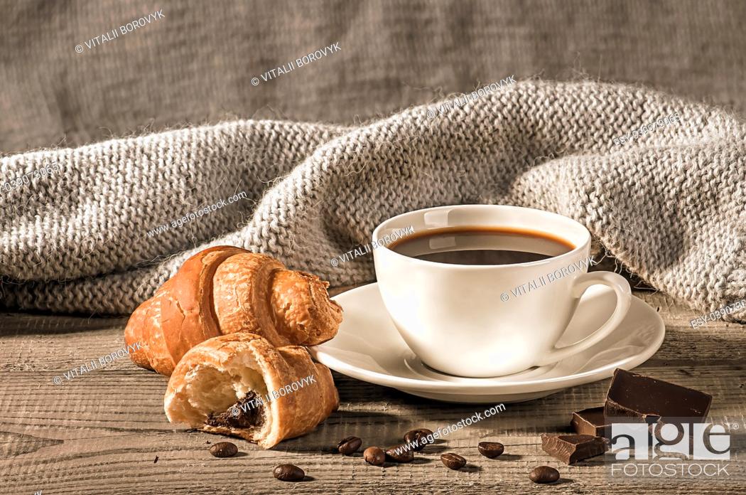 Stock Photo: Coffee with croissants on the background of a woolen scarf. Grains of coffee next to the cup. Several pieces of dark chocolate next to each other.