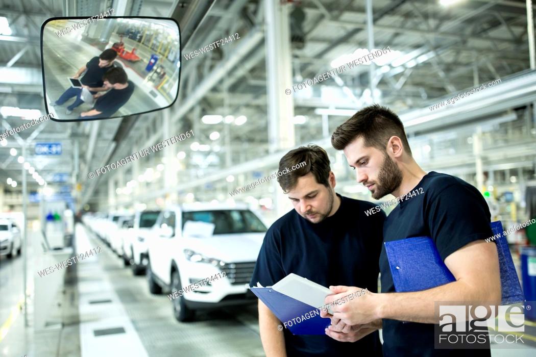 Stock Photo: Two colleagues working in modern car factory using clipboard and tablet.