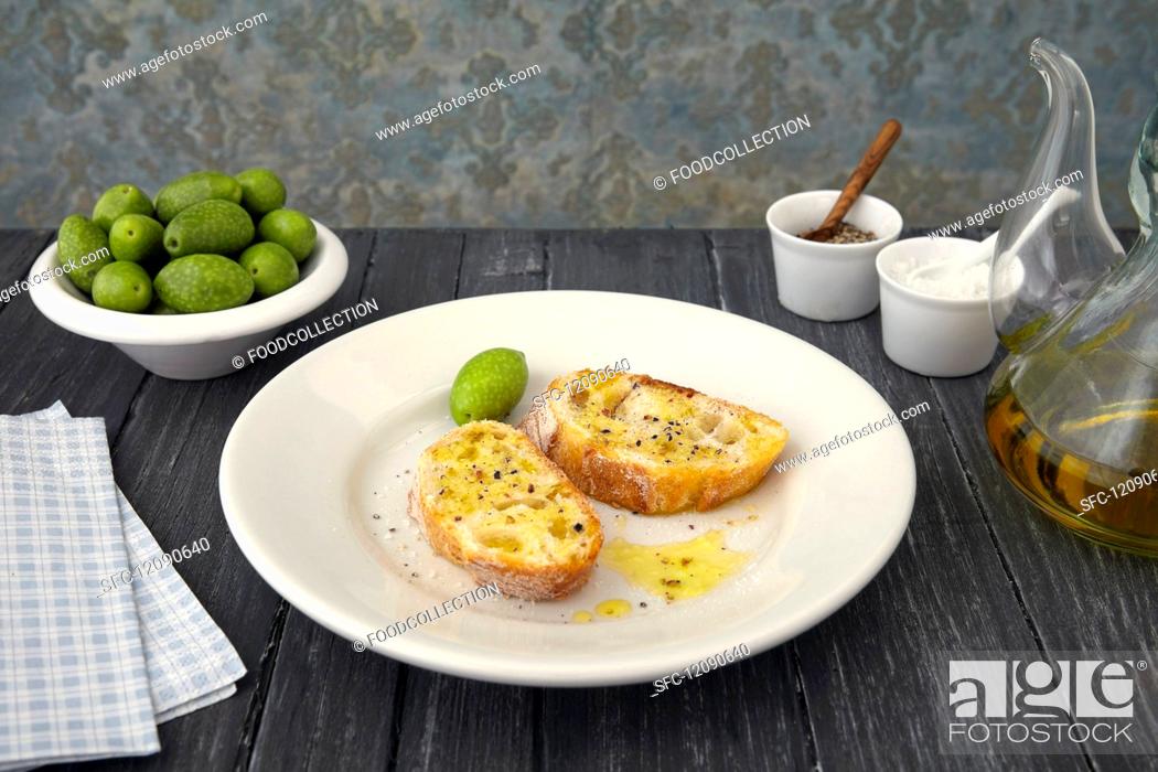 Stock Photo: Two baguette slices with olive oil and olives (Arbosana, Chile).