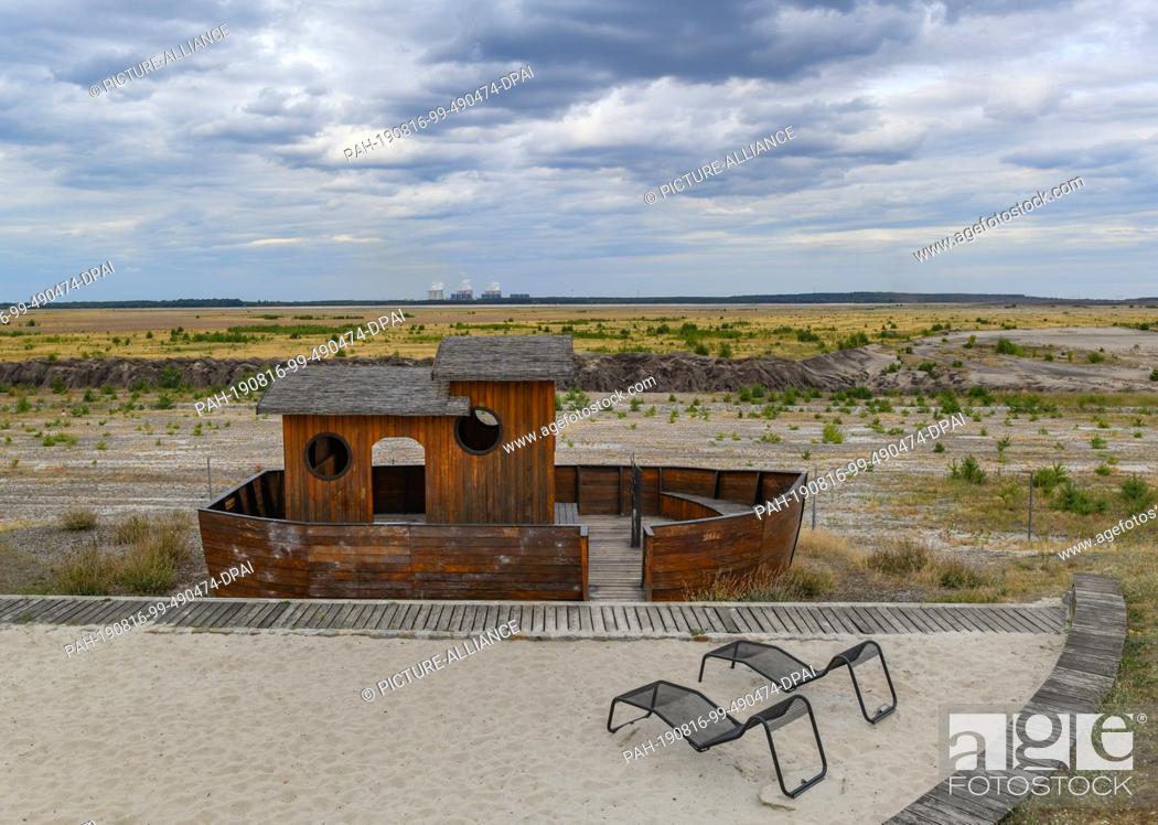 Stock Photo: 15 August 2019, Brandenburg, Cottbus: A small wooden ship stands symbolically at the edge of the former open-cast lignite mine Cottbus-Nord.