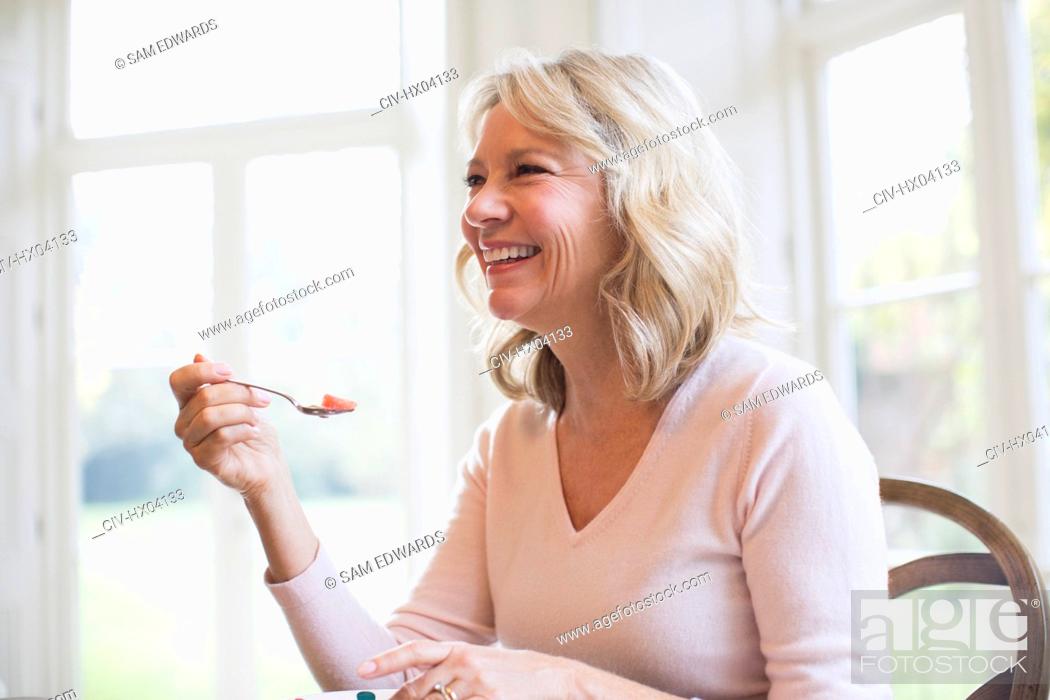 Photo de stock: Happy mature woman eating fruit.