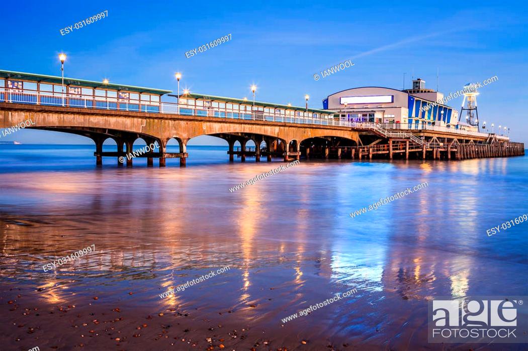 Stock Photo: The lights of Bournemouth Pier at night reflected in the wet sand on the beach. Dorset England UK Europe.