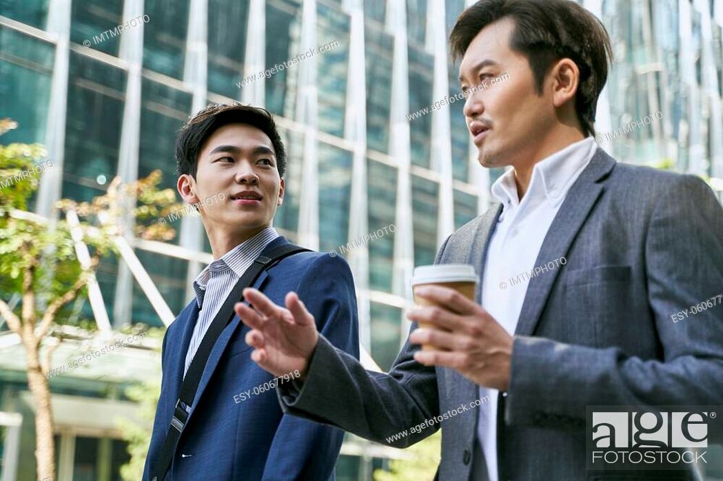 Photo de stock: side view of two asian corporate executives discussing business while walking in street in downtown of modern city.