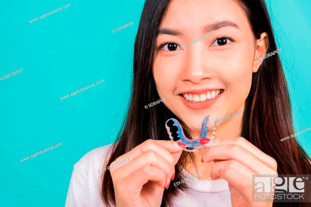 Stock Photo: Teeth retaining tools after removable braces, Portrait young Asian beautiful woman smiling holding silicone orthodontic retainers for teeth.