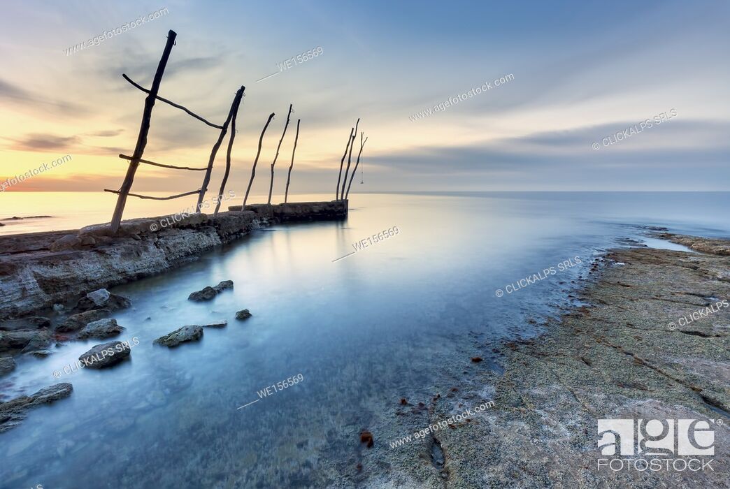 Stock Photo: Europe, Croatia, Istria, Adriatic coast, Umag, village Savudrija. The bay at sunset with traditional wooden poles for fishing boats.