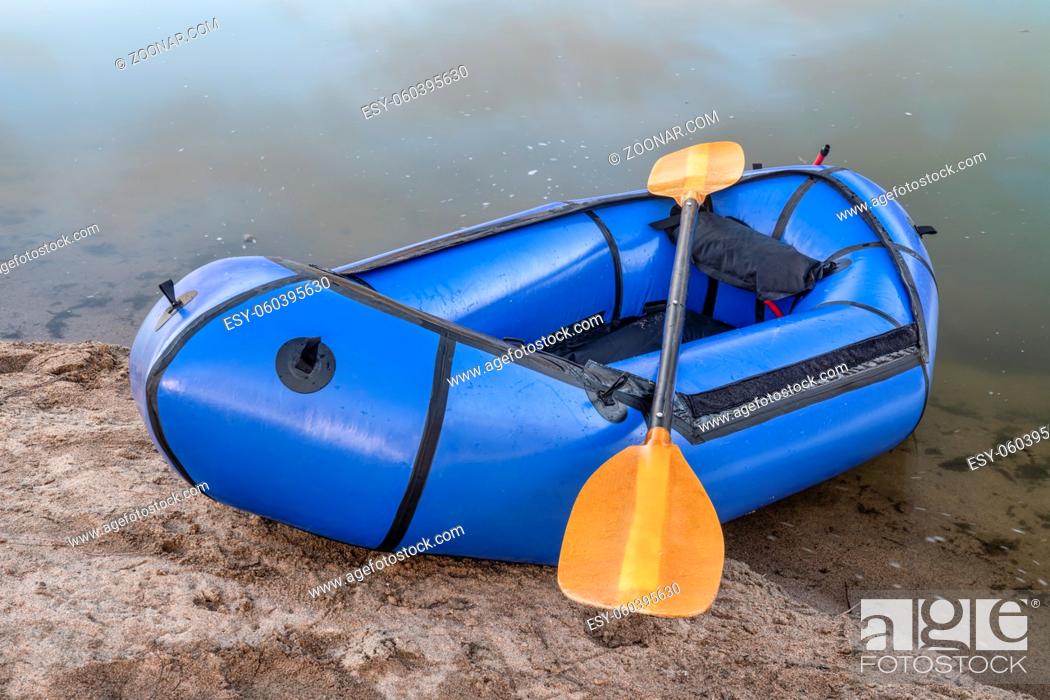 Stock Photo: inflatable packraft (one-person light raft used for expedition or adventure racing) with a paddle on lake shore in Colorado.