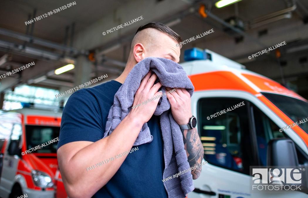 Stock Photo: 10 January 2019, North Rhine-Westphalia, Gelsenkirchen: The fireman Tom wipes the sweat from his face with a towel after his run in the fire station.