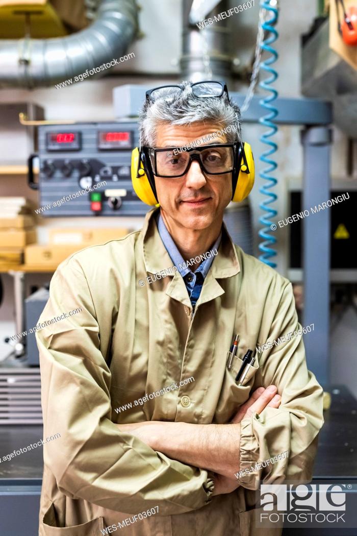 Stock Photo: Mature male owner with arms crossed at workshop.