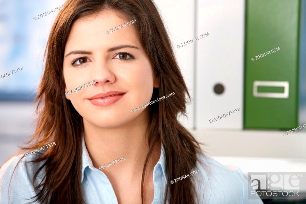 Stock Photo: Pretty professional girl smiling at camera, face in closeup, office background.