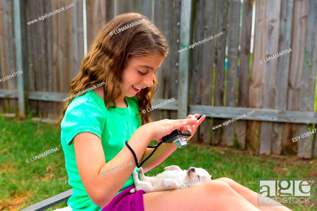 Stock Photo: Kid girl taking photos to puppy dog pet with camera in outdoor backyard.