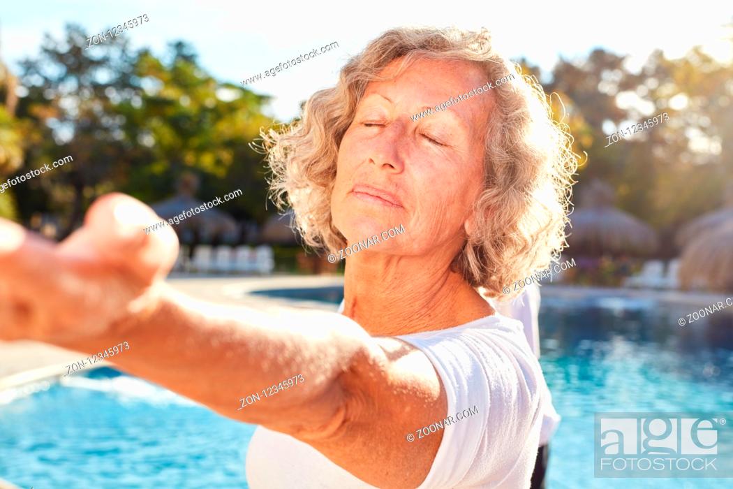 Stock Photo: Senior Frau macht eine Yoga Meditation am Pool im Wellness Workshop.