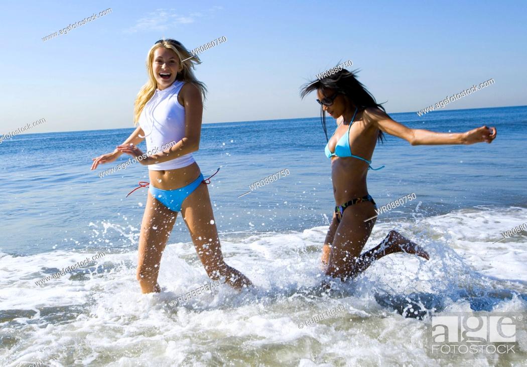Stock Photo: Profile of two young women wading in the sea water.