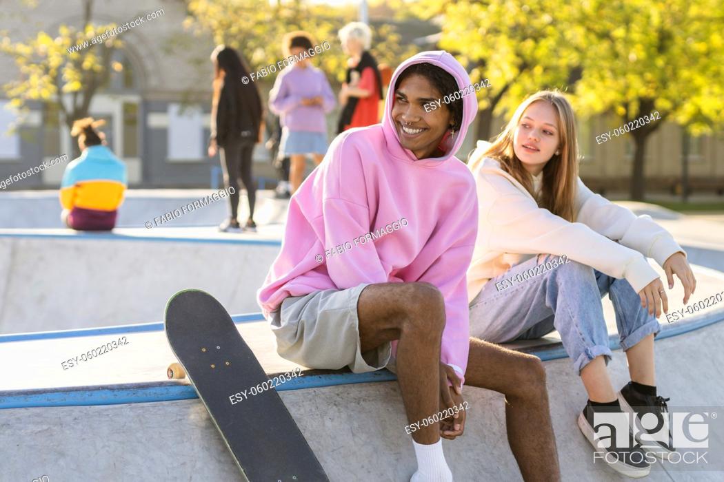 Imagen: Multicultural group of young friends bonding outdoors and having fun - Stylish cool teens gathering at urban skate park.