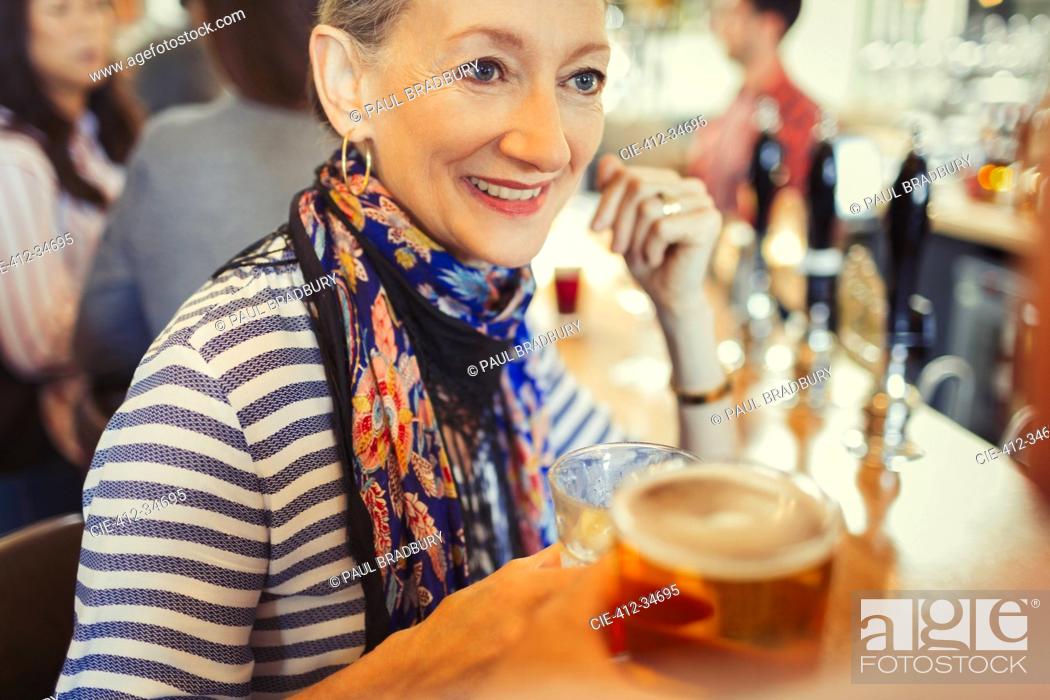 Stock Photo: Senior woman drinking beer at bar.