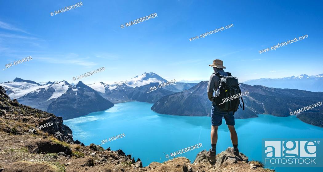 Stock Photo: Young man looking into the distance, view of mountains and glacier with lake Garibaldi Lake, summit Panorama Ridge, Guard Mountain and Deception Peak.