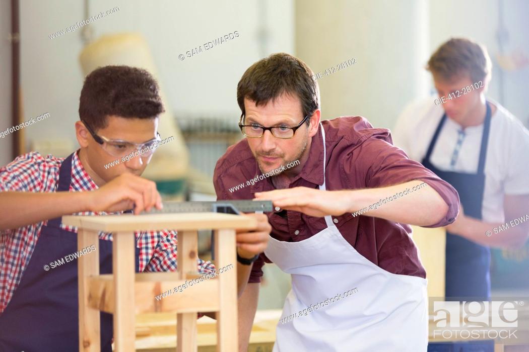 Stock Photo: Focused carpenters measuring wood in workshop.
