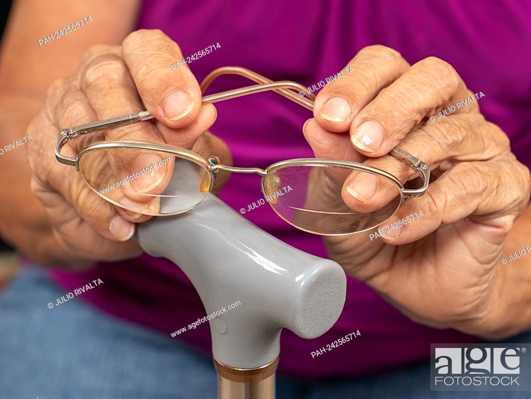 Stock Photo: Old wrinkled woman hands holding glasses on a walking stick || Model approval available.