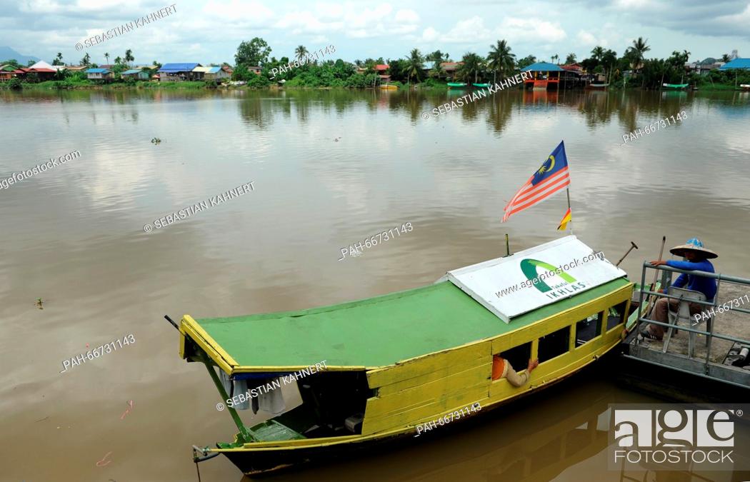 Stock Photo: A ferryman is waiting for passengers next to his wooden boat on the shore of the Sarawak River in Kuching, Malaysia, 21 October 2014.