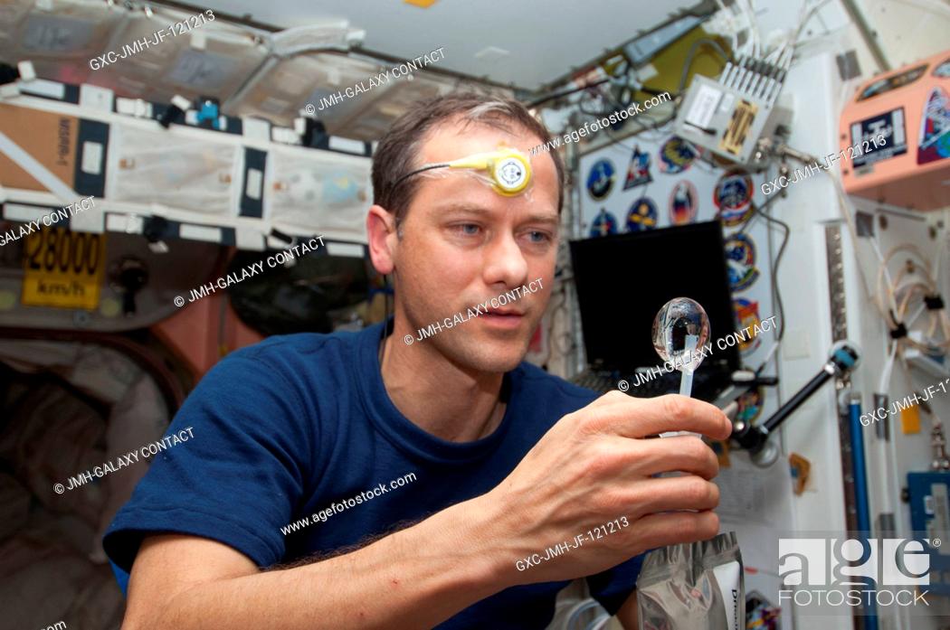 Stock Photo: NASA astronaut Tom Marshburn, Expedition 34 flight engineer, squeezes a water bubble out of his beverage container in the Unity node of the International Space.