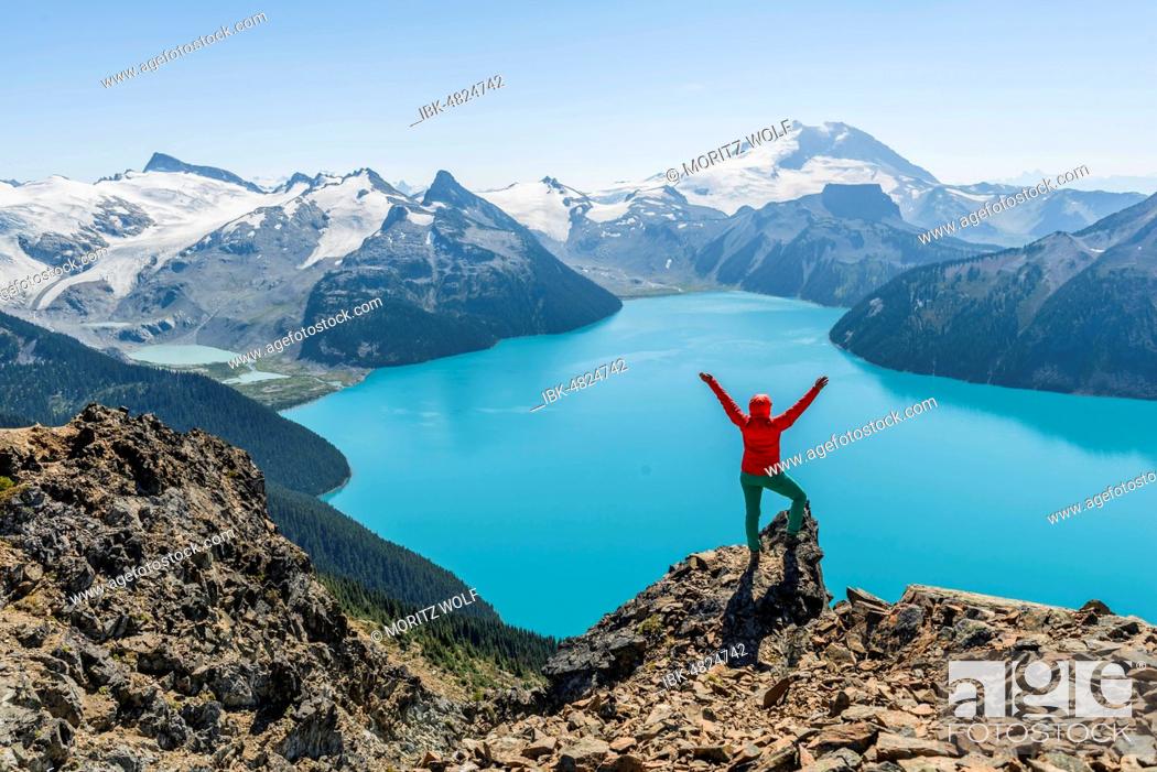 Stock Photo: View from the Panorama Ridge hiking trail, hiker on a rock stretches arms into the air, Garibaldi Lake, Guard Mountain and Deception Peak, back glacier.