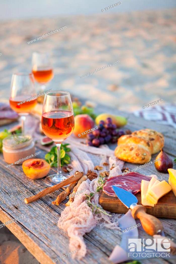 Stock Photo: Picnic on the beach at sunset in the style of boho, food and drink conception.