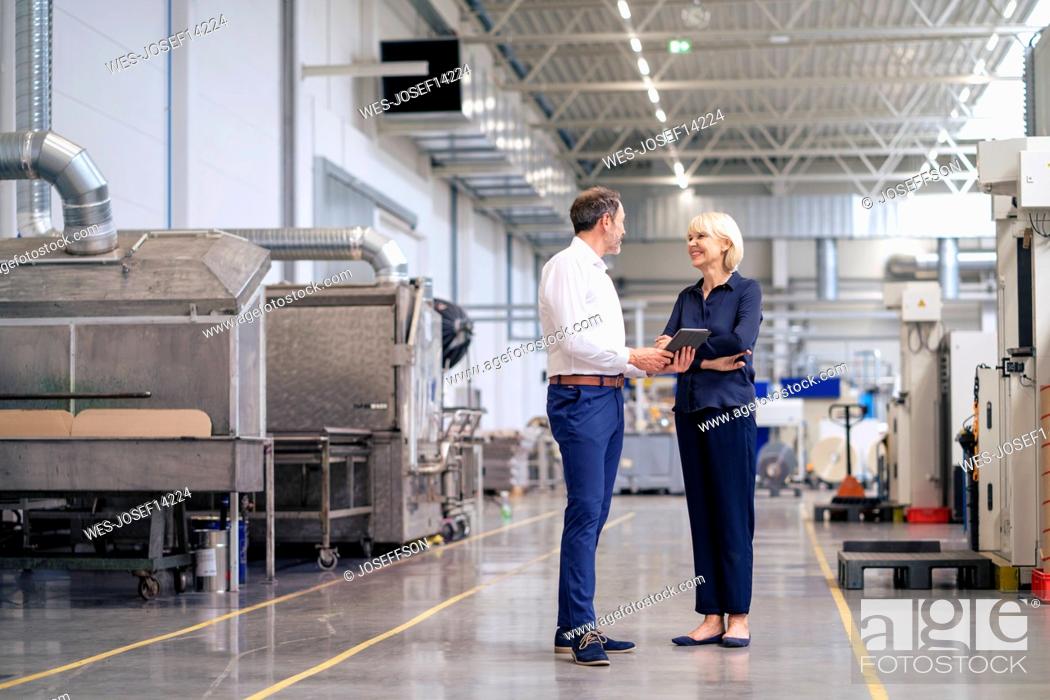 Stock Photo: Mature businessman holding tablet PC discussing with colleague in factory.