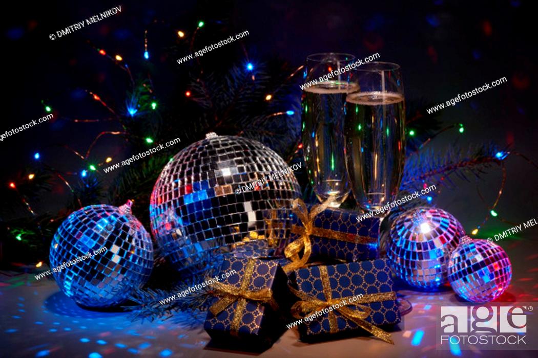 Stock Photo: Champagne flutes, mirror balls (disco ball), fir branch, on dark background with colorful LED lights garland. New Year and Christmas.