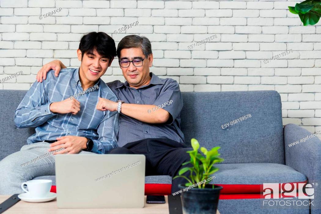 Stock Photo: Asian senior businessman with laptop computer discuss together with young team in office. Father man and his son sit on sofa talking chatting on video call.