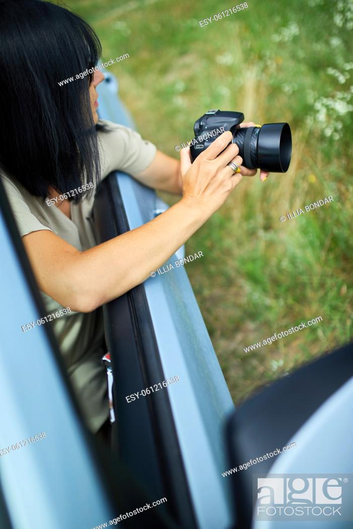 Stock Photo: Woman photographer sitting in the car and photographing a flower field landscape, travel female take photo, space for text.