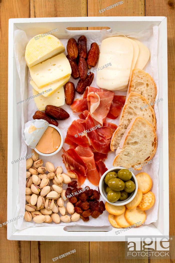 Stock Photo: cheese with prosciutto, bread, fruits and nuts.