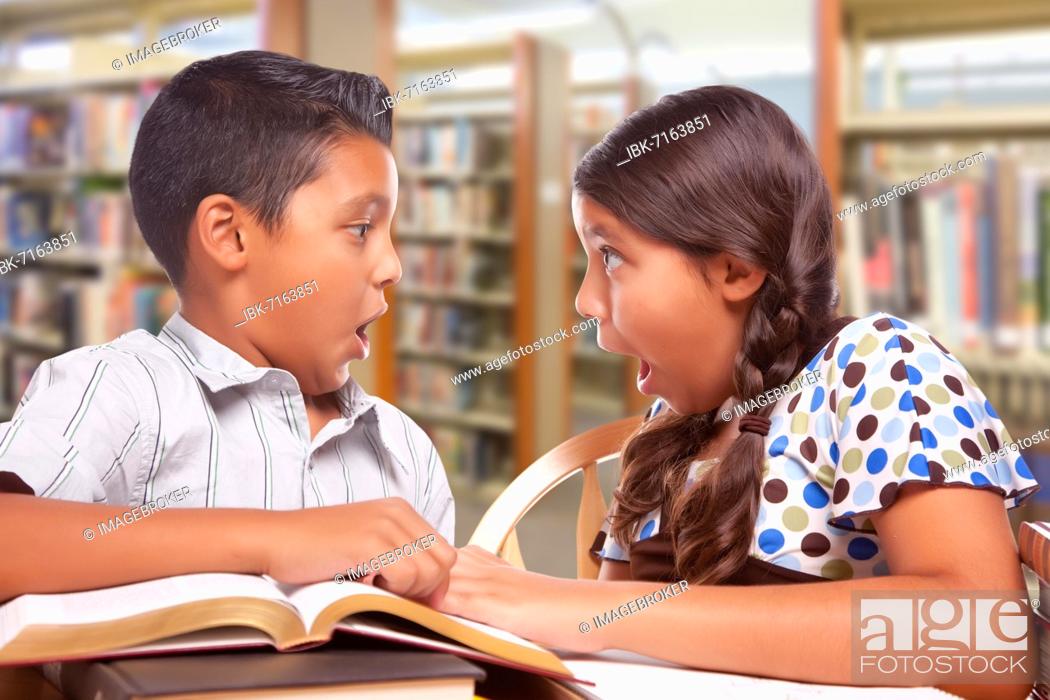 Imagen: Hispanic boy and girl having fun studying together in the library.