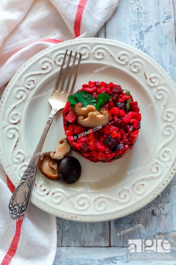 Stock Photo: Traditional Russian salad with marinated mushrooms on a white plate.