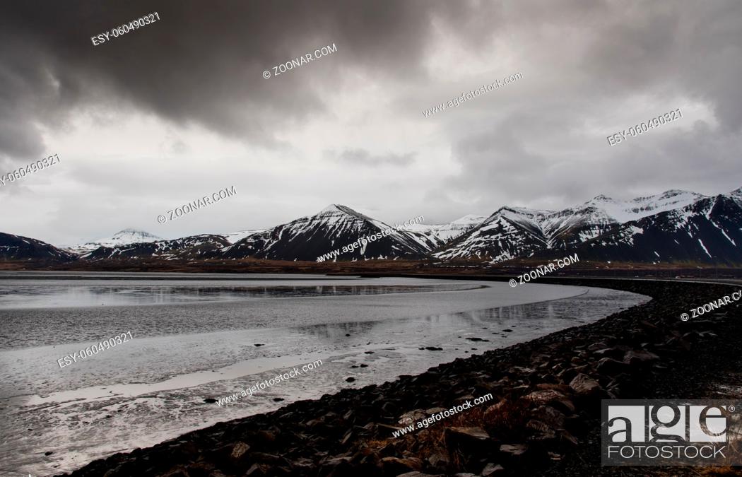 Stock Photo: Typical Icelandic dramatic landscape with frozen lake and mountains covered in snow in Iceland.