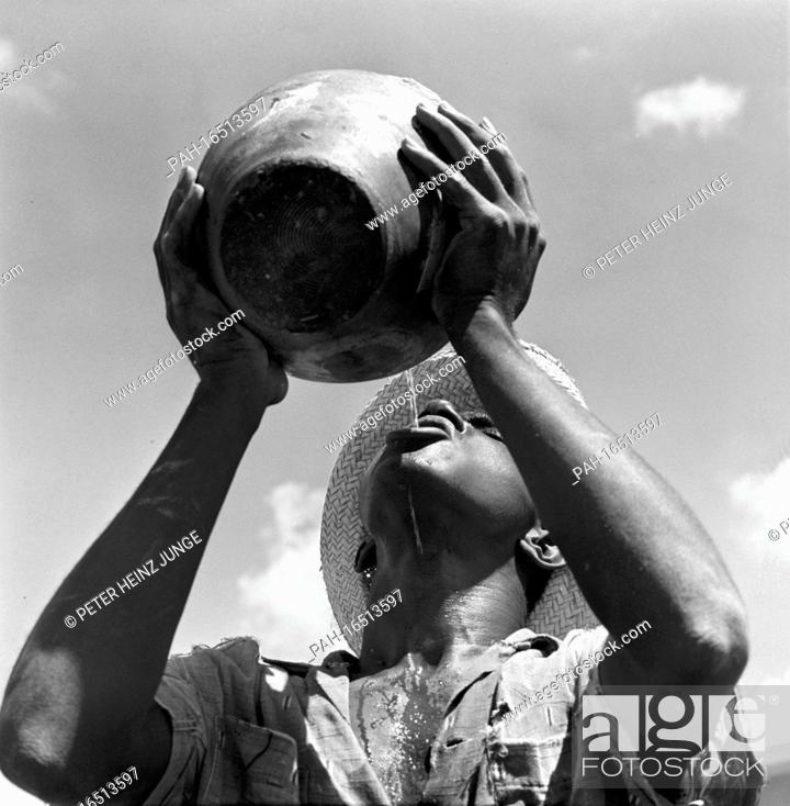 Stock Photo: A Cuban man satiates his thirst with water from a large clay jug, photographed in 1962 in Pinar del Rio Province. Photo: Heinz Junge.