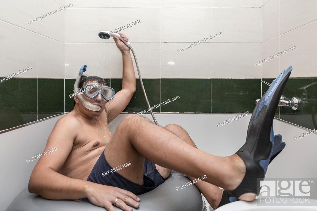 Stock Photo: Adult man in snorkeling mask and flippers sitting on swimming ring and taking shower while pretending to rest on beach during self isolation at home.