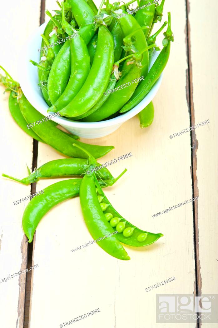 Stock Photo: hearthy fresh green peas over a rustic wood table.