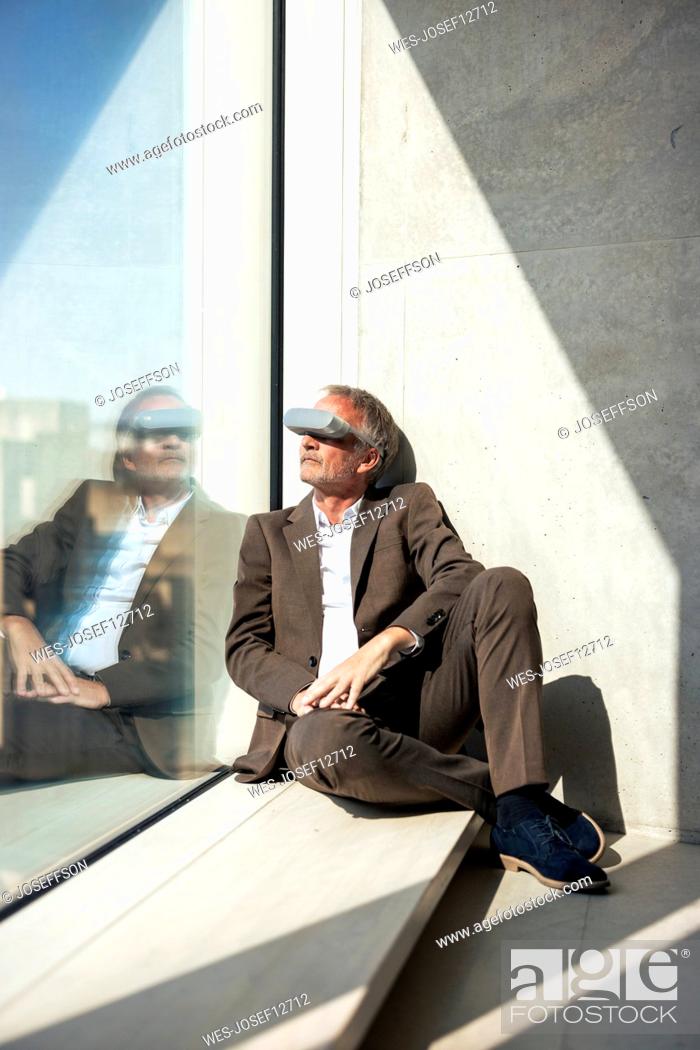 Photo de stock: Senior businessman watching through smart glasses by window in office.