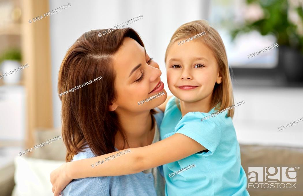Stock Photo: little daughter hugging her mother on sofa at home.