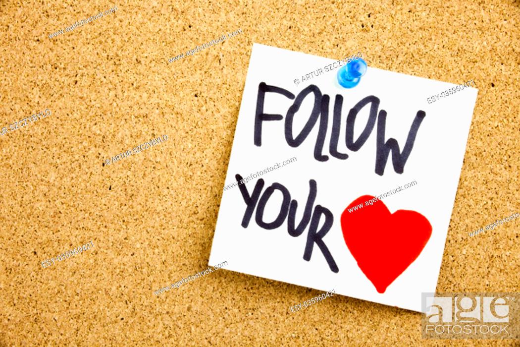 Stock Photo: Phrase FOLLOW YOUR HEART in black ext on a sticky note pinned to a cork notice board.