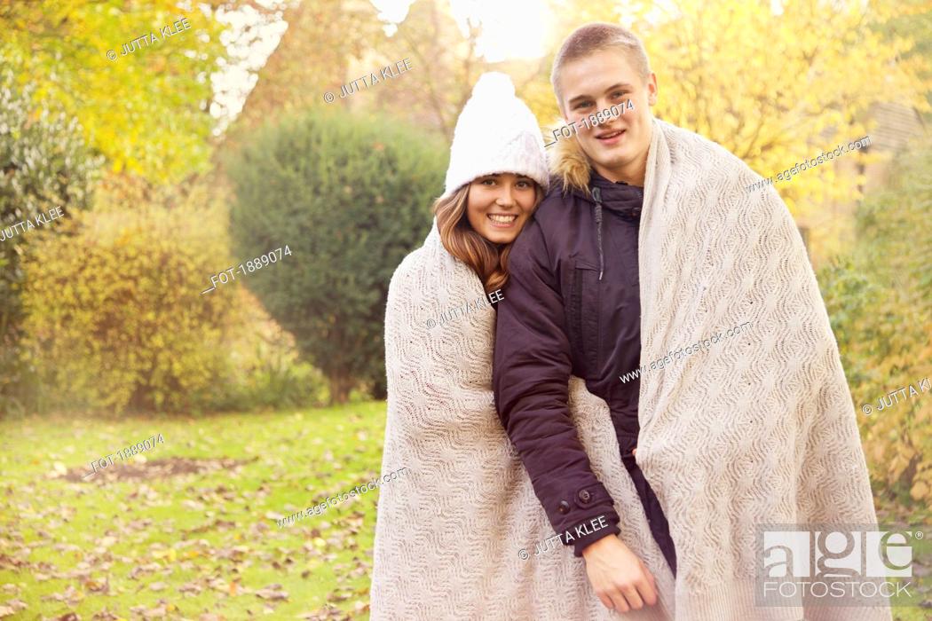 Stock Photo: Portrait happy teenage couple wrapped in blanket in autumn park.