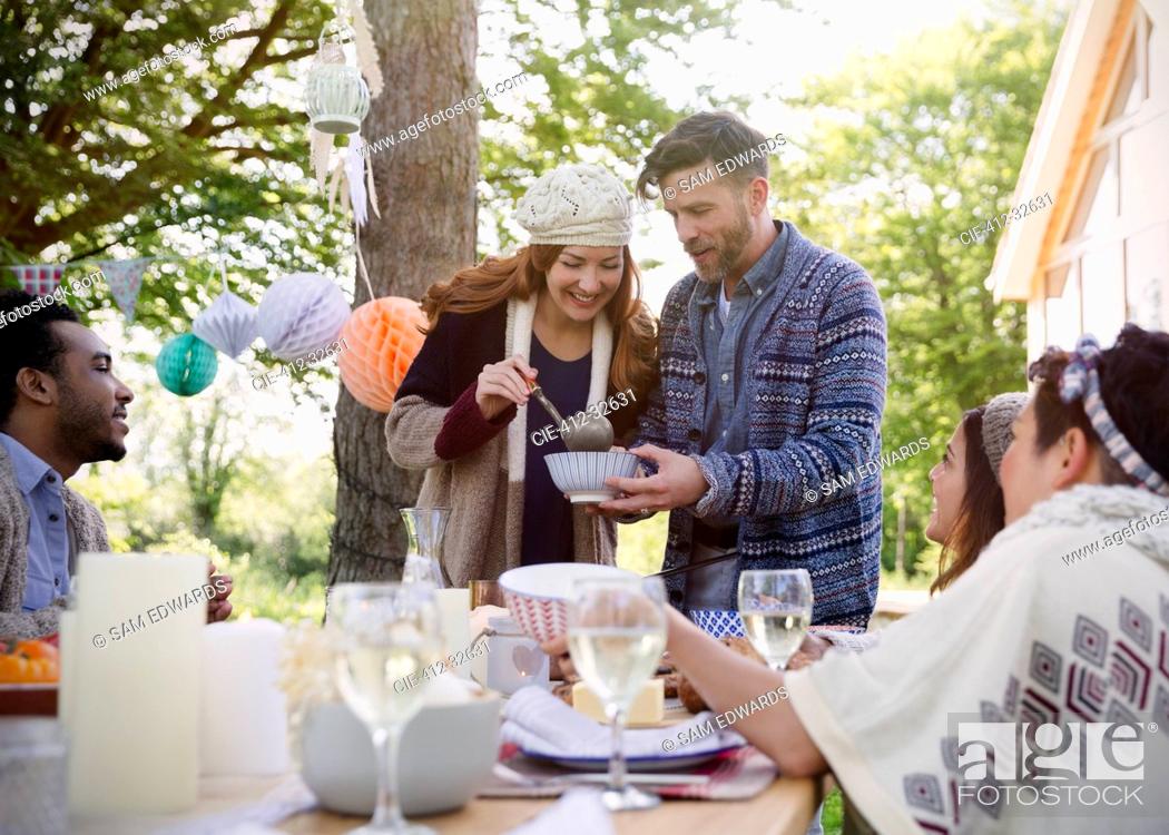 Stock Photo: Couple serving lunch to friends at patio table.