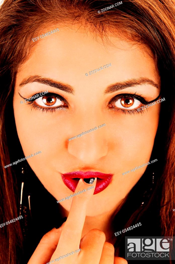 Stock Photo: A gorgeous face of a young woman with big eyes and a finger in her mouths with red lips looking at the camera.